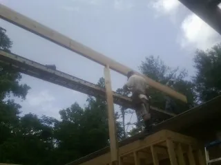 Carpenter setting a ridge beam over a new addition frame — Ice Dam Removal by Roofing Brothers in Elkwood