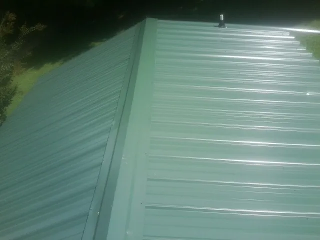 New green metal panels meeting at the ridge of a roof — Flat Roof Repair work by our crew in Elkwood