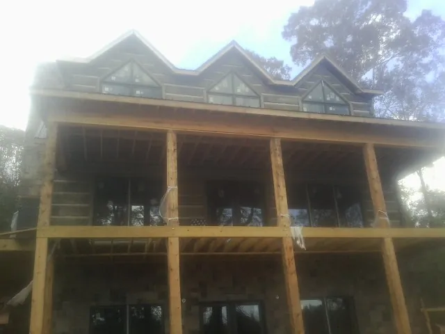 Dormers and porch framing on a large log home under construction — Roof Coating work by our crew in Elkwood