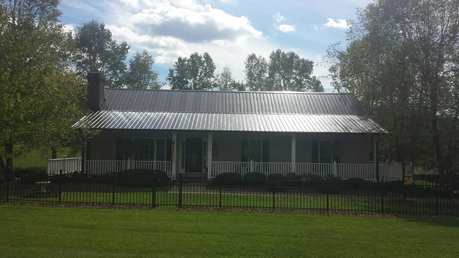 Gray metal roof on a brick ranch with a full width front porch — Gutter Guard Installation work by our crew in Elkwood