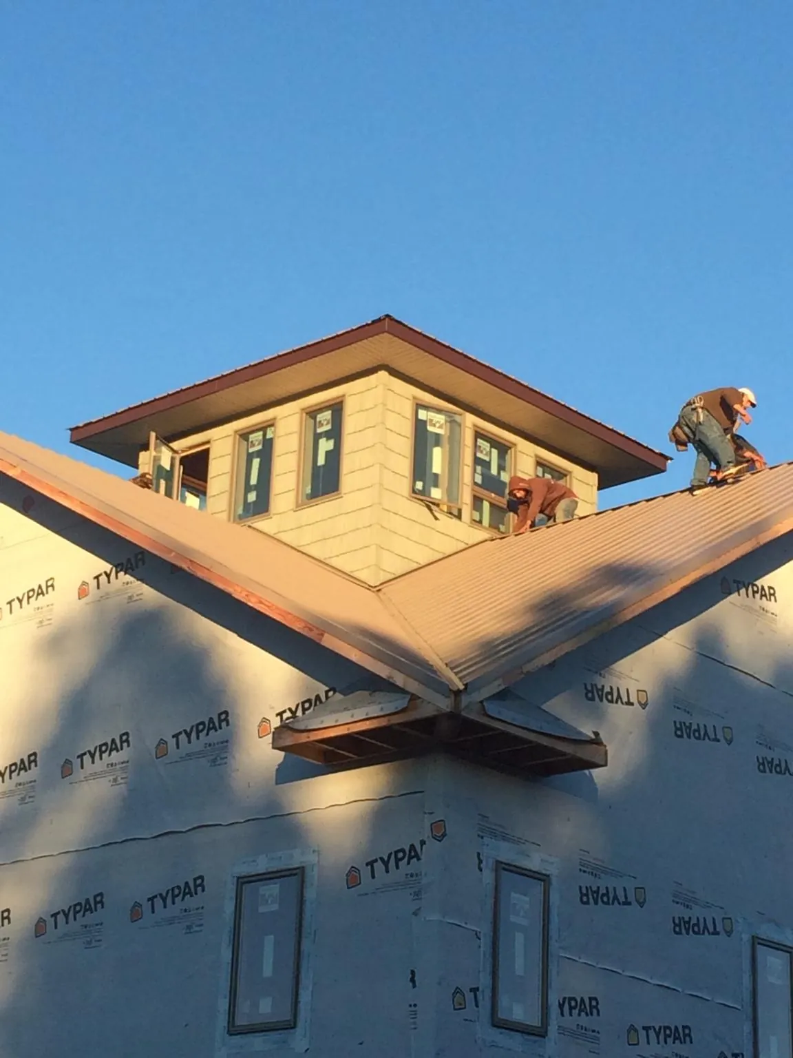 Roofers working around a rooftop cupola on a new metal roof at sunset — Roof Waterproofing in Elkwood by Roofing Brothers